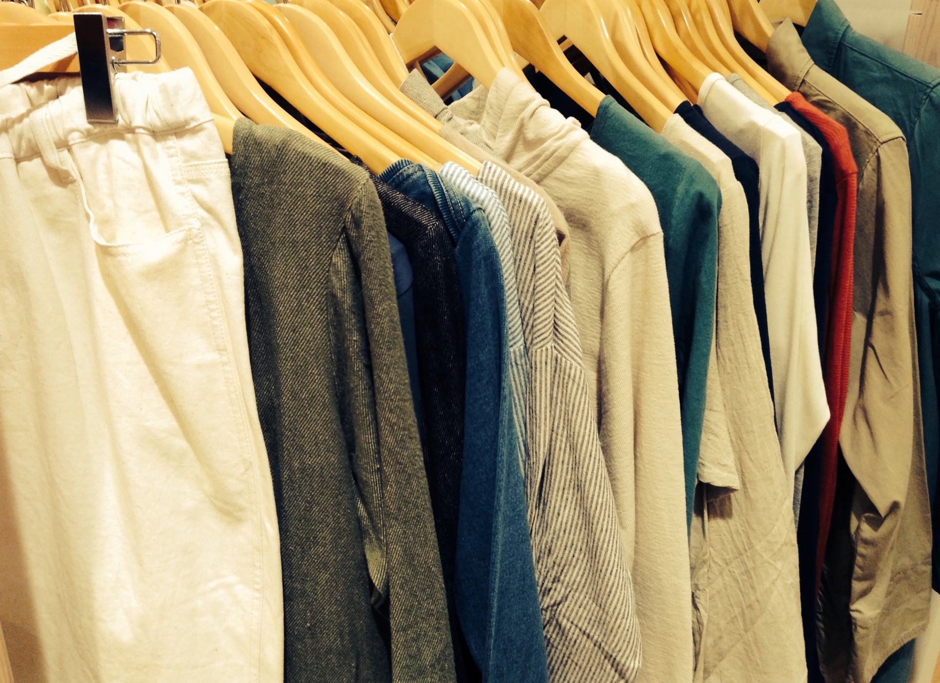 ハンガーにかけられてずらりと並んだ衣服の写真
